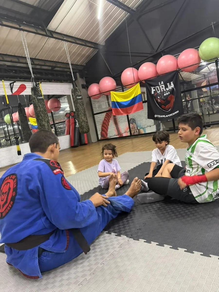 Niños estirando con el coach en la clase de BJJ Kids de La Forja MMA